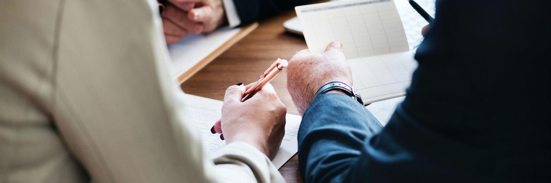 Close up of two people's arms near paperwork